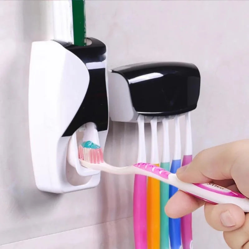 Automatic toothpaste dispenser with wall-mounted holder for toothbrushes and colorful cups in a bathroom setting.